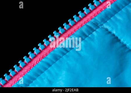 Gros plan sur une fermeture éclair bleue et rose sur une veste bleue. Image plein format, demi-noir Banque D'Images