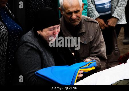 Mère pleure, alors qu'elle tient le drapeau ukrainien entre ses mains. La famille, la famille et les amis assistent aux funérailles de Sergey Titov, 32 ans, sergent de la Garde nationale d'Ukraine, tué par des bombardements russes à Orikhiv. Banque D'Images