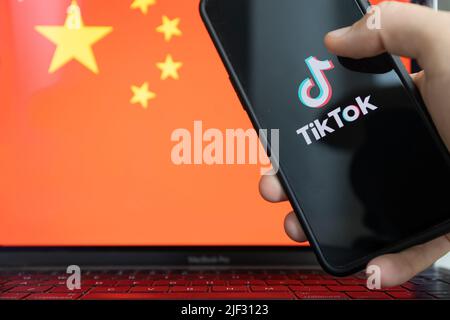 Application TikTok sur smartphone et drapeau chinois en arrière-plan. Banque D'Images