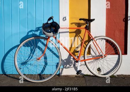 Orange Bicycle appuyé contre le mur coloré de boatshed, Wellington, Île du Nord, Nouvelle-Zélande Banque D'Images