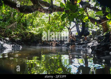 Les baigneurs s'imprégnent de la piscine naturelle de sources chaudes à l'intérieur d'un tube de lave à Pohoiki Black Sand Beach, sur la Big Island d'Hawaï. Banque D'Images