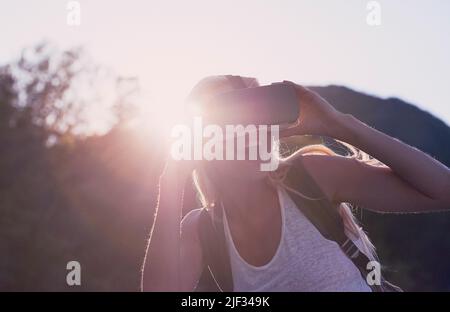 Jeune femme excitée en vacances avec un casque VR. Jeune femme en vacances enthousiaste à l'idée d'utiliser un casque VR. Jeune femme heureuse utilisant un casque VR pendant la randonnée Banque D'Images