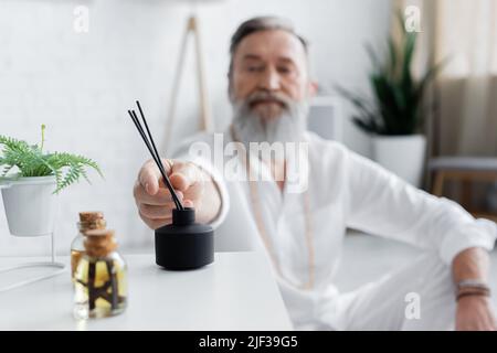 concentration sélective des huiles essentielles et diffuseur avec des bâtons d'arôme près du gourou de guérison floue Banque D'Images