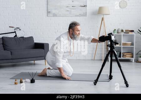 entraîneur de yoga ajustement de l'appareil photo numérique près des bâtons d'arôme et des huiles aromatisées à la maison Banque D'Images