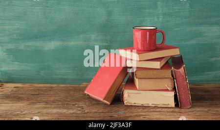 Livre ouvert, livre rigide vintage et tasse de café sur fond vert. Éducation, lecture, concept de recherche. Banque D'Images