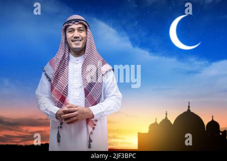 Homme arabe portant le keffiyeh debout avec la silhouette de la mosquée et le fond de la scène de nuit Banque D'Images