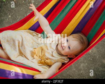 Enfant dans un hamac arc-en-ciel Banque D'Images