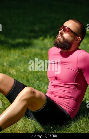 Cycliste prenant le repos dans les herbes vertes. L'été, bonne humeur. Banque D'Images