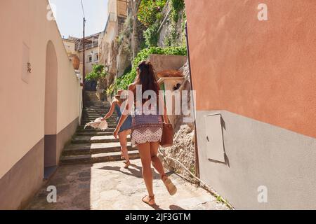 Prise de vue en longueur de deux amis méconnaissables marchant dans une allée d'Amalfi Banque D'Images