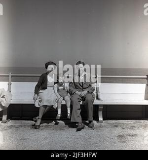 1953, historique, mère et père avec leur jeune fils, assis ensemble sur un banc en bois au bord de la mer, Margate, Kent, Angleterre. ROYAUME-UNI. Banque D'Images