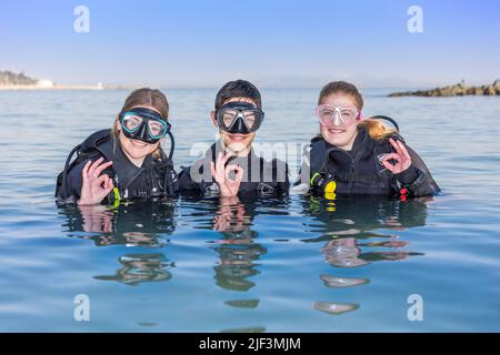 Des plongeurs souriants dans la mer, face à l'appareil photo avec leurs masques de plongée sur montrer le signe OK Banque D'Images