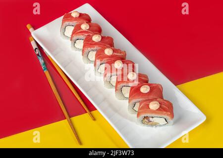 Nigiri sushi sets, Uramaki, Californie, Philadelphie, sur une assiette blanche. Près du gingembre et du wasabi. Sauce soja dans un bol blanc. Sur fond coloré. Co Banque D'Images