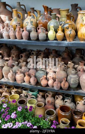 Beaucoup de pots en céramique d'artisanat et vases sur les étagères et fleurs de plante à l'intérieur. Vaisselle. Banque D'Images