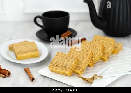 Lapis legit, Spekkoek, Spekuk, gâteau indonésien avec mille couches. Servi sur une assiette blanche avec thé, gros plan. Banque D'Images