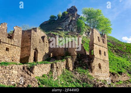 Ruines d'anciens bâtiments en pierre sous les rochers dans le village abandonné de Gamsutl Banque D'Images