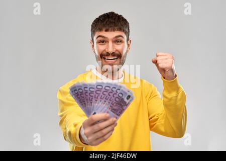 joyeux jeune homme avec de l'argent célébrant le succès Banque D'Images