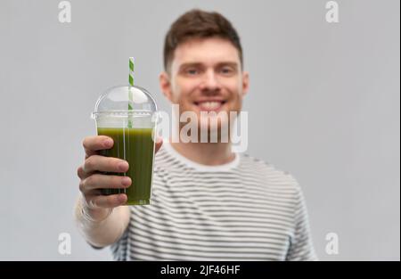 homme buvant du smoothie vert dans une tasse jetable Banque D'Images