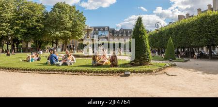 Place des vosges, Paris. Les gens se détendent par une chaude journée près de la fontaine de la plus ancienne place de Paris, en France. Banque D'Images