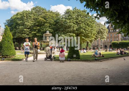 Place des vosges, Paris. Les gens se détendent par une chaude journée près de la fontaine de la plus ancienne place de Paris, en France. Banque D'Images