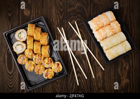 Plateaux en plastique avec divers rouleaux et baguettes sur une table en bois en gros plan Banque D'Images