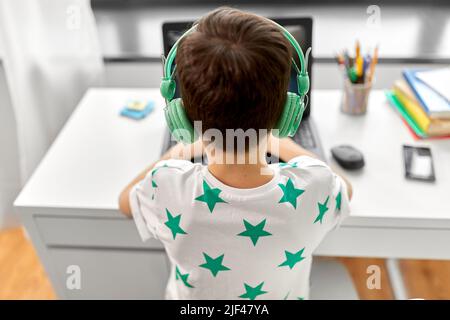 Boy in headphones playing video game on laptop Banque D'Images