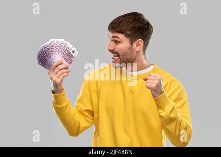 joyeux jeune homme avec de l'argent célébrant le succès Banque D'Images