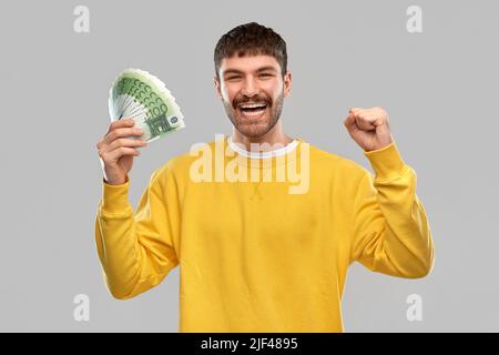 joyeux jeune homme avec de l'argent célébrant le succès Banque D'Images