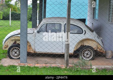 Coléoptère, vieux véhicule semi-détruit de couleur blanche avec des roues en alliage léger dans un garage en maçonnerie en photo panoramique dans les terres agricoles au Brésil, en Amérique du Sud Banque D'Images