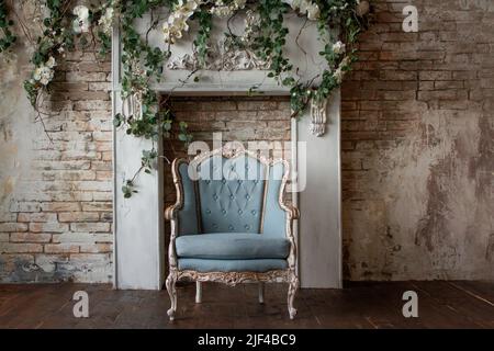 Vieux mobilier de fauteuil antique contre un mur gris clair grunge, stuc, et vignes avec des fleurs Résumé chambre vide. Banque D'Images