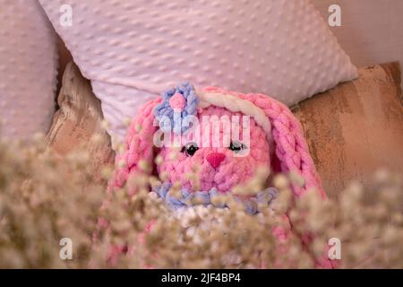 jouet tricoté de lapin rose sur le canapé. Crochet animal. Amigurumi. Placer pour le texte. Banque D'Images