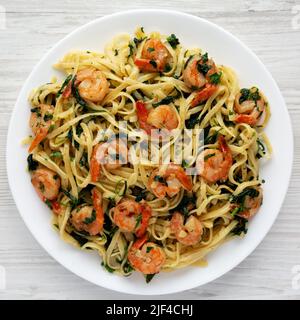 Pâtes à la crevette à l'ail au citron maison sur une assiette sur fond de bois blanc, vue du dessus. Pose à plat, en hauteur, par le dessus. Banque D'Images