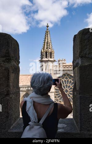 Vue arrière d'un touriste mature prenant une photo de la basilique Saint-Nazaire à Carcassonne Banque D'Images