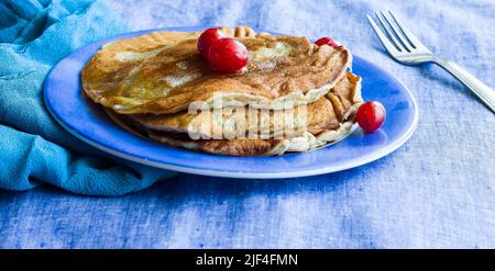 Vue directe sur une pile de crêpes Banana surmontée de cerises et de beurre fondu. Concept de petit déjeuner végétalien sain.gros plan des crêpes. Banque D'Images