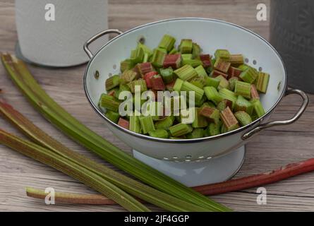 Colaner plein de Rhubarb haché sur une surface avec des bâtons de rhubarb tiré sur la surface Banque D'Images
