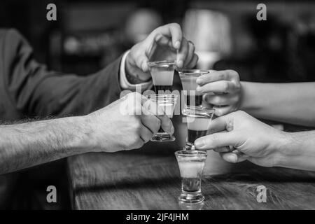 Cocktail à la discothèque. Groupe d'amis tequila shot verres au bar. Mains mâles verres de grenaille ou de liqueur. Les amis boivent une dose ou une liqueur. Cinq Banque D'Images