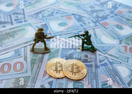 Les criminels de guerre utilisant la btc, bitcoin ou crypto-monnaie photo de fond de concept. Deux symboles bitcoin sur les dollars américains avec deux soldats de figurine. Sélectionnez Banque D'Images