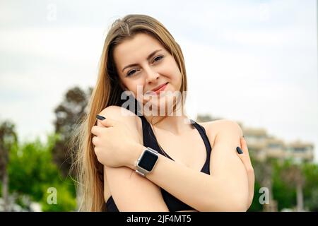 Jeune femme caucasienne portant un soutien-gorge de sport noir debout sur le parc de la ville, en plein air se embrassant heureux et positif, souriant confiant. Amour de soi et se Banque D'Images