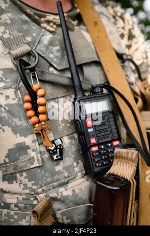 Talkie-walkie et rosaire avec une croix dans la poitrine d'un soldat, la guerre et la foi en Dieu, Dieu et la guerre en Ukraine. Banque D'Images