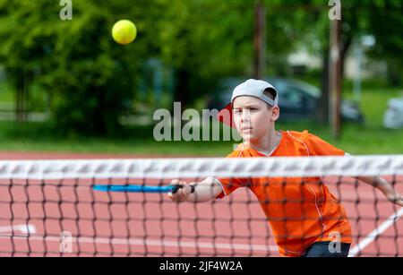 Enfant avec une raquette de tennis sur le court de tennis. Formation pour les jeunes enfants, enfants en bonne santé. Affiche horizontale sur le thème du sport, cartes de vœux, en-têtes, site Web et Banque D'Images