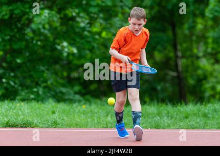 Enfant avec une raquette de tennis sur le court de tennis. Formation pour les jeunes enfants, enfants en bonne santé. Affiche horizontale sur le thème du sport, cartes de vœux, en-têtes, site Web et Banque D'Images