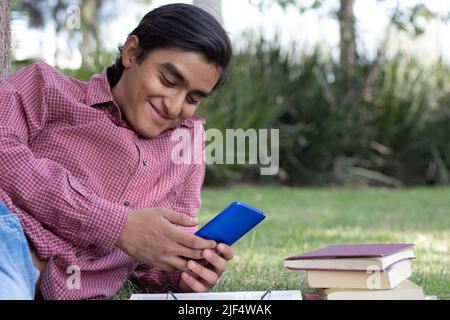 Jeune homme avec des lunettes lisant dans le parc Banque D'Images