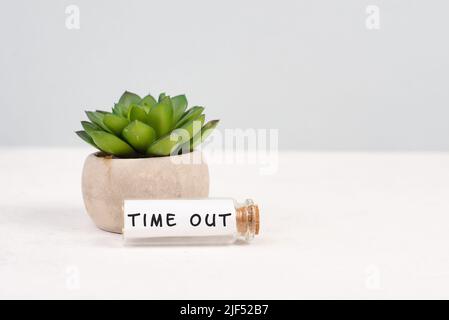 Cactus dans un pot sur fond gris, bouteille en verre avec l'expression délai d'attente, équilibre de vie professionnelle, bureau à un bureau Banque D'Images