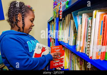 Une fille afro-américaine choisit les livres du Dr Seuss dans une bibliothèque lors d'un programme post-scolaire, le 28 février 2013, à Columbus, Mississippi. Banque D'Images