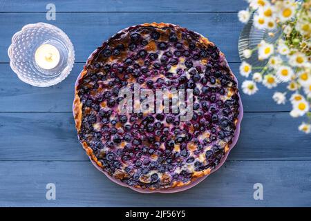 Mustikkapiirakka, un Pie de bleuets finlandais. Plat, vue de dessus sur une table en bois bleu avec des fleurs blanches. Banque D'Images