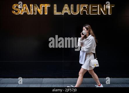 Un piéton parle au téléphone alors qu'elle passe devant le magasin de luxe de la marque française Yves Saint Laurent (YSL) à Hong Kong. Banque D'Images