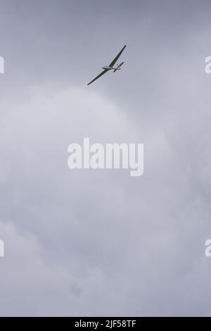 Planeur volant haut dans les nuages sombres Banque D'Images