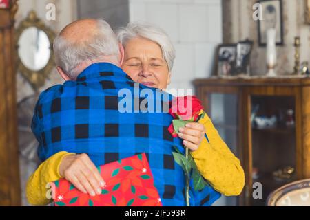 Femme caucasienne senior embrassant son mari reconnaissant pour présente moyenne proximité salon ancienneté et concept de vacances. Photo de haute qualité Banque D'Images