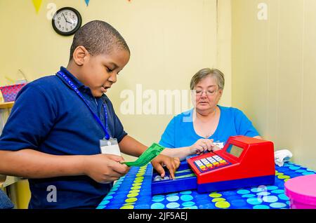 Un tuteur bénévole aide un étudiant à faire des changements avec une caisse de jouets dans un centre de tutorat après l'école, le 28 février 2013, à Columbus, Mississippi. Banque D'Images