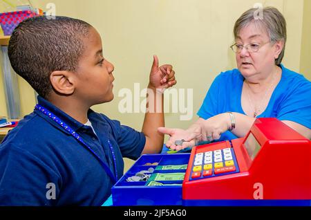 Un tuteur bénévole aide un étudiant à faire des changements avec une caisse de jouets dans un centre de tutorat après l'école, le 28 février 2013, à Columbus, Mississippi. Banque D'Images