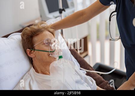 Médecin mettant un masque respiratoire sur une patiente avec Covid-19 dans la salle d'hôpital Banque D'Images